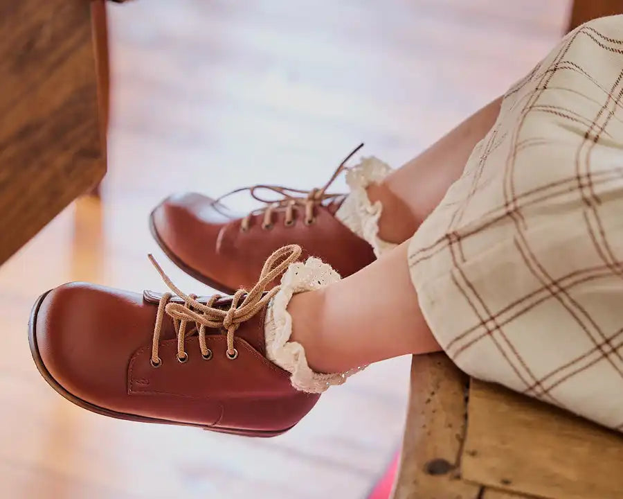Brown leather boots with lace trim and cream-colored laces.