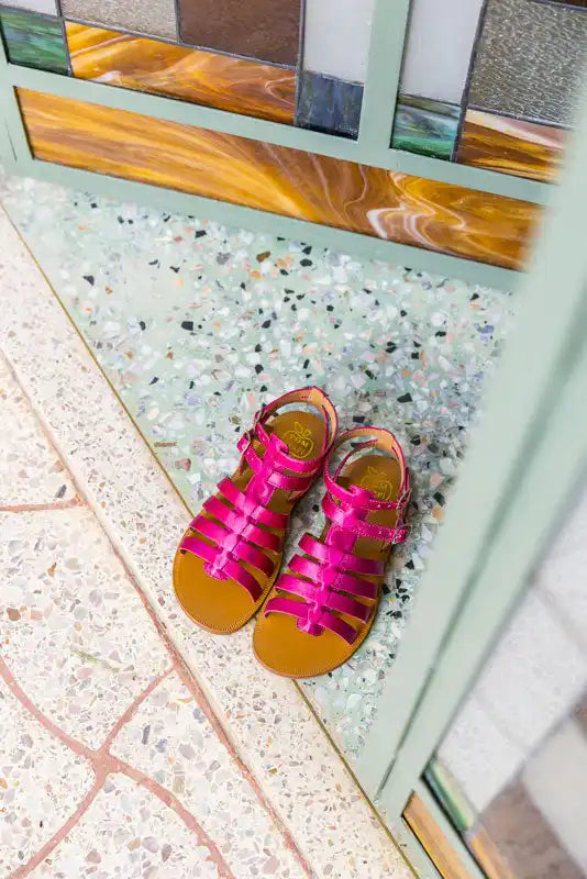 Hot pink gladiator sandals with brown leather soles.