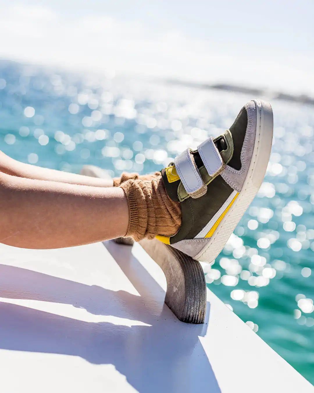 Baskets à velcro avec des accents jaunes portées avec une chaussette brune.