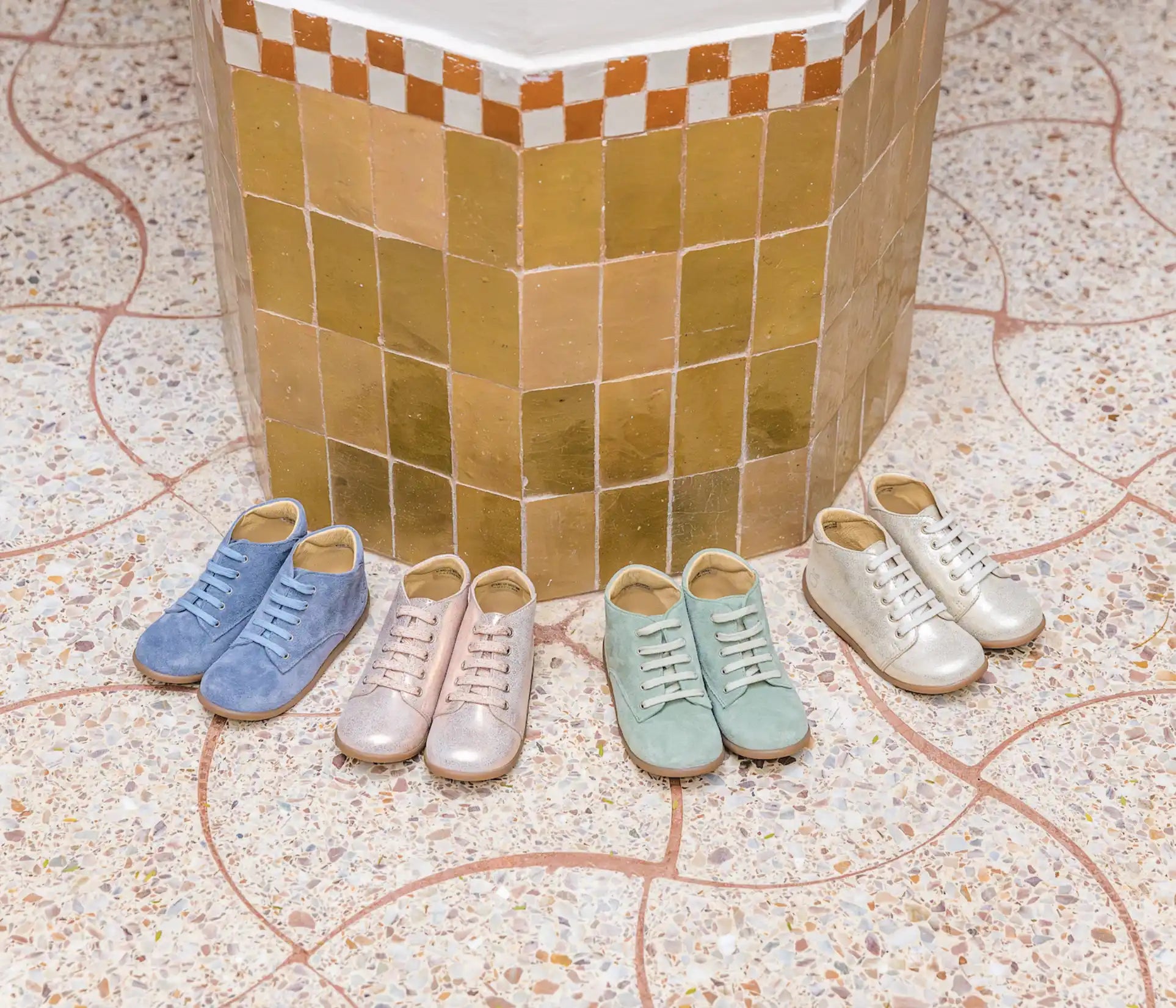 Four pairs of pastel sneakers arranged in a semicircle against a tiled wall.