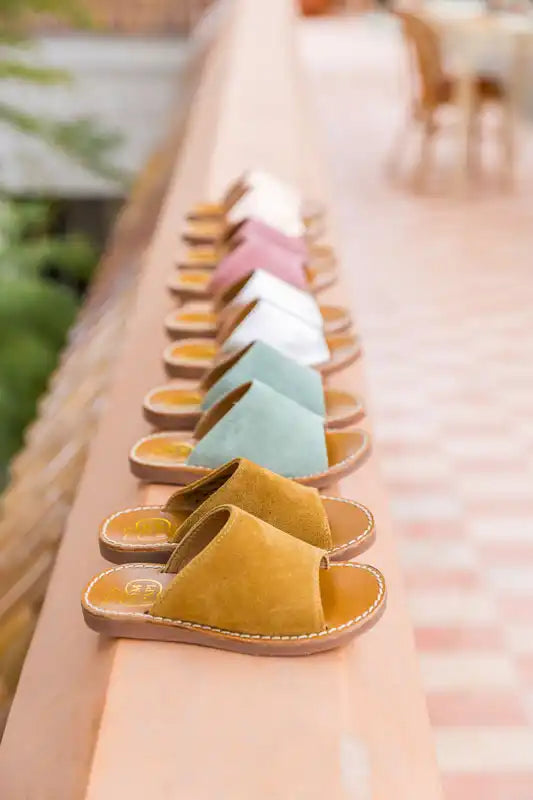 A row of colorful, laceless suede sandals in pastel yellow, mint, white and pink.