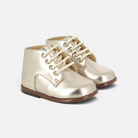 Chaussures premiers pas Pom d'Api en cuir doré avec lacets, bout rond renforcé et semelle antidérapante.